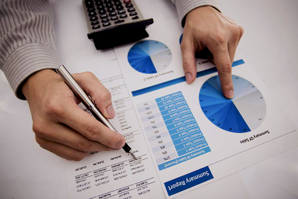 Homem fazendo anotações em um papel com gráficos e estatísticas analisando o resultado dos seus estudos