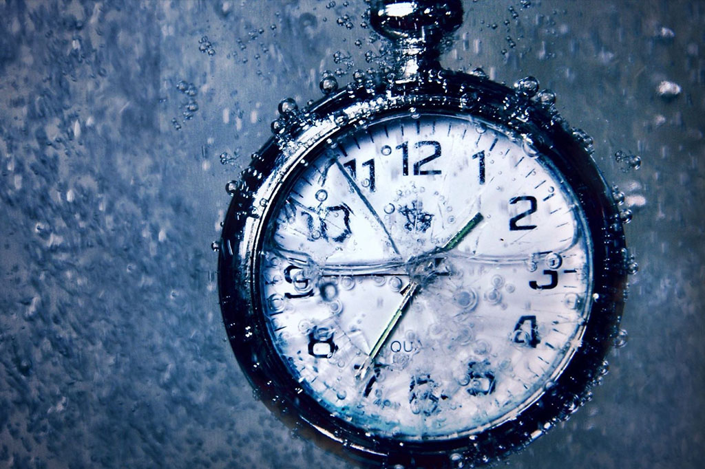 Um relógio tipo cronômetro submerso todo suado para representar horas líquidas de estudos