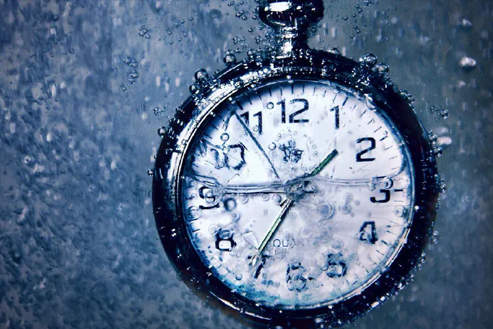 Um relógio tipo cronômetro submerso todo suado para representar horas líquidas de estudos